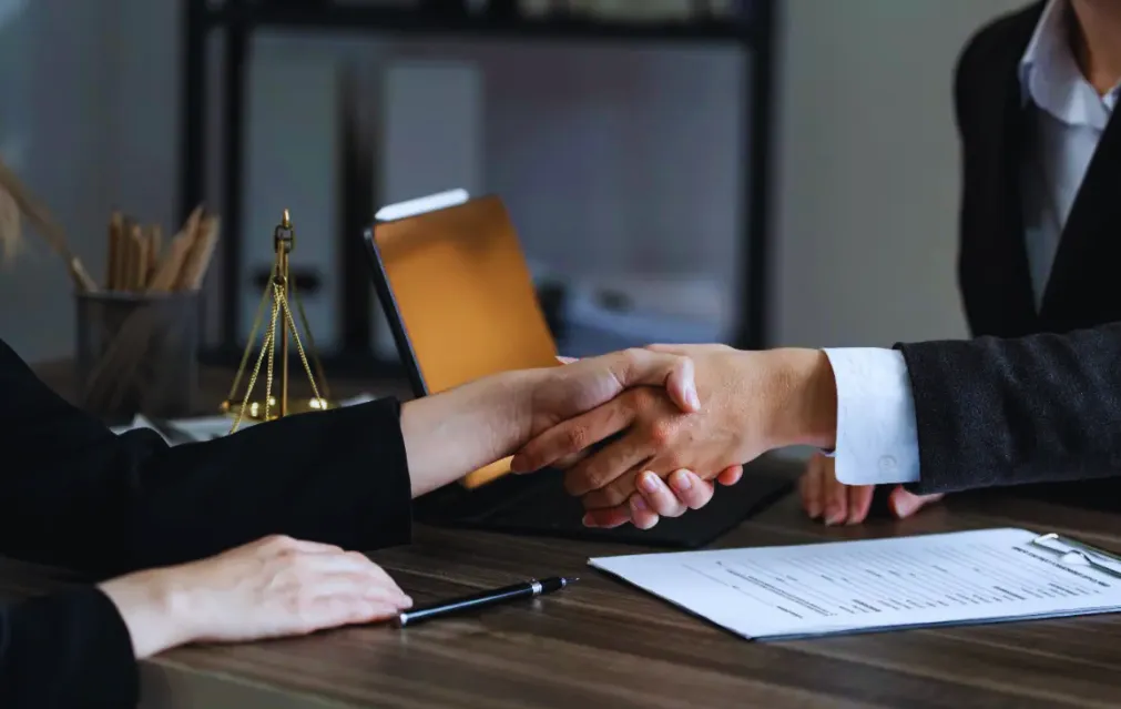 Business partners signing a contract with a corporate attorney.